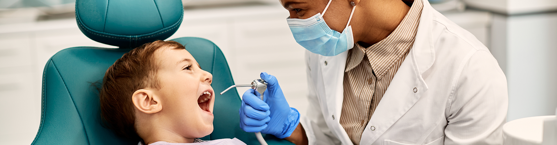 dentist using dental tools in child's mouth.